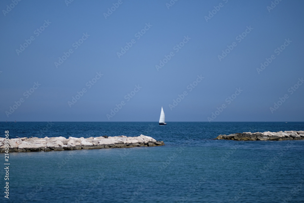 Fototapeta premium Yacht with a white sail against the background of the sea and the blue sky