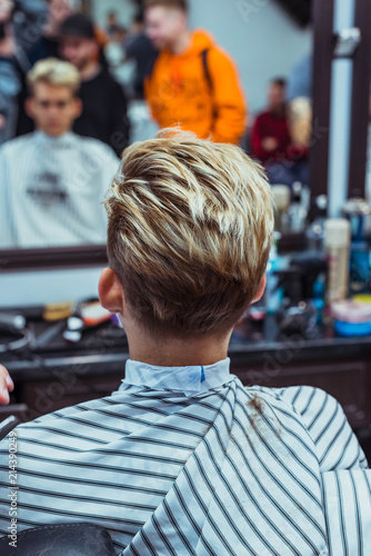 Barber in Barbershop shear hair electric car to young guy hipper for fashionable hairstyle. photo