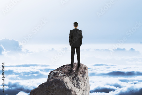 businessman on rock above clouds