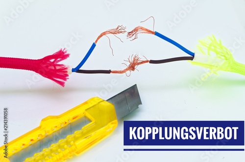 Bunte Kabel die getrennt und notdürftig geflickt wurden und einem Cuttermesser mit Aufschrift in deutsch Kopplungsverbot in Englisch coupling ban photo