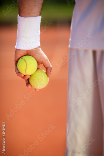 Tennis balls in tennis player's hand, close up . © luckybusiness