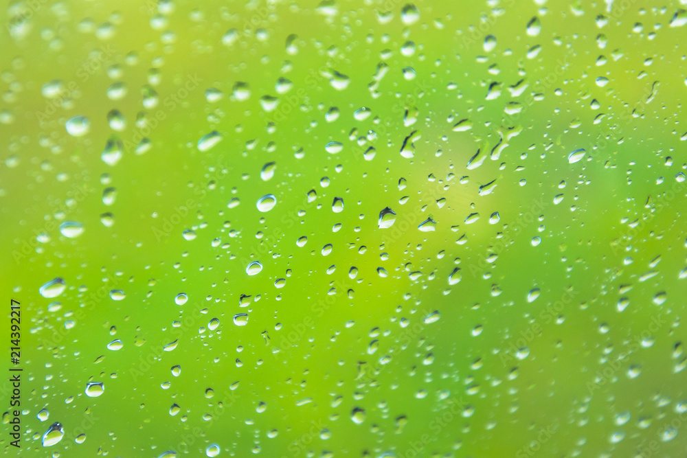 Drops of water on a glass against a background of green grass meadows.
