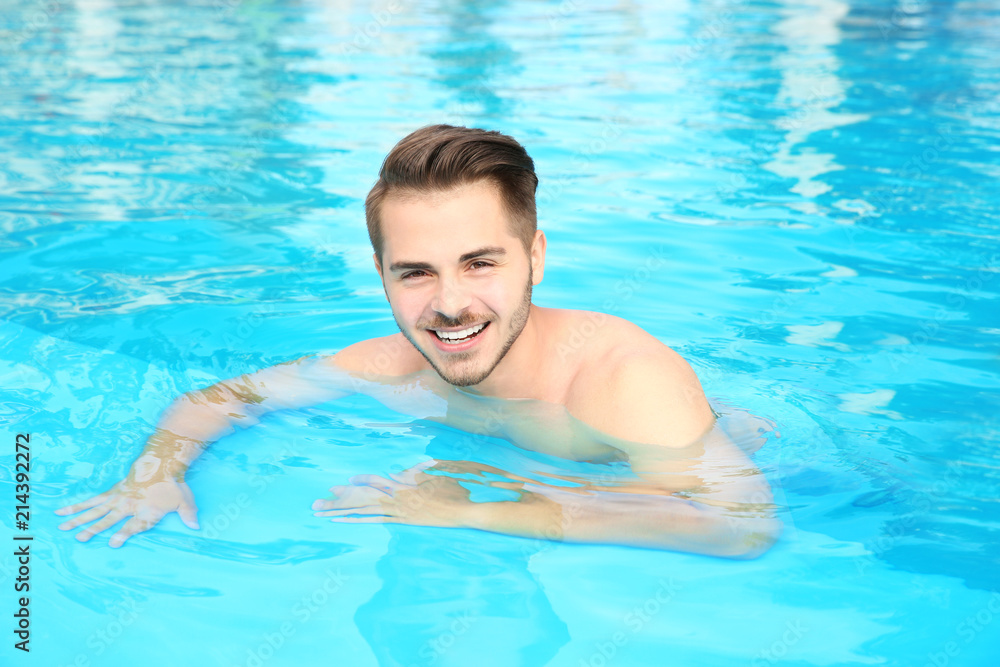 Young handsome man in swimming pool on sunny day