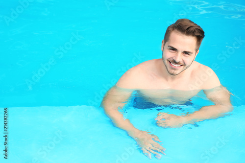 Young handsome man in swimming pool on sunny day