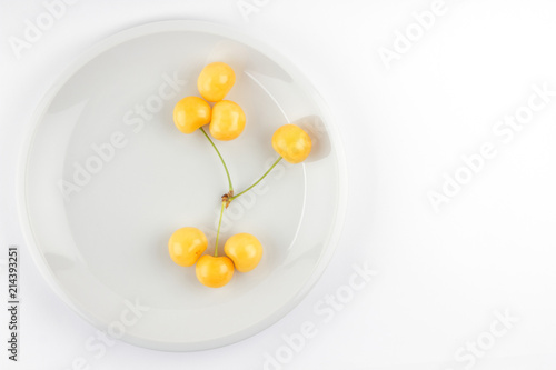 Yellow cherries on white plate, fresh cherries on white background, yellow berries in minimalism style, vegetarian food, isolated