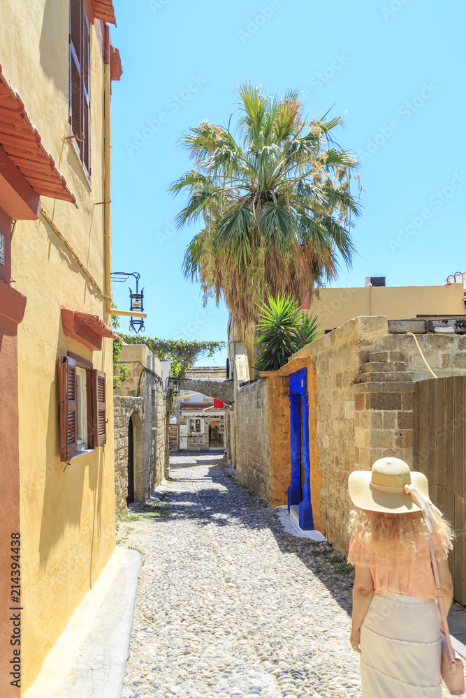 Naklejka premium Blonde walking in historic streets of old town Rhodes, Dodecanese, Greece