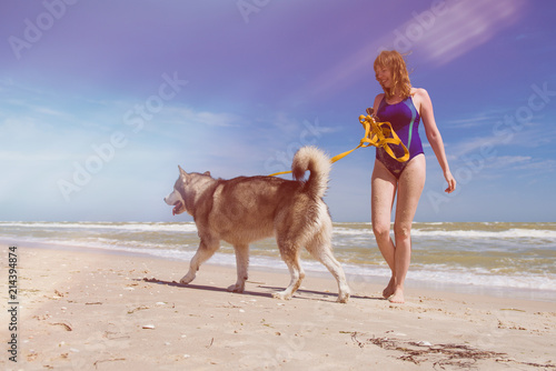 Woman walk with husky dog at beach