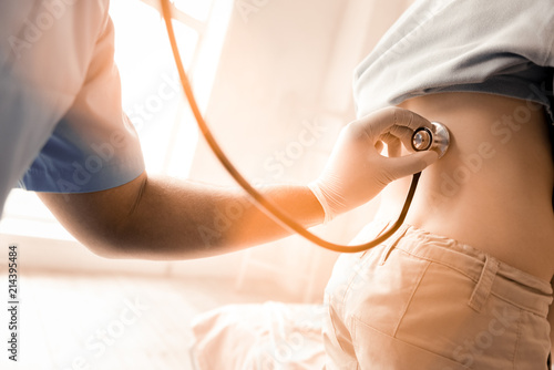 Start breathing. Little boy standing in semi position and rolling T-shirt while visiting doctor