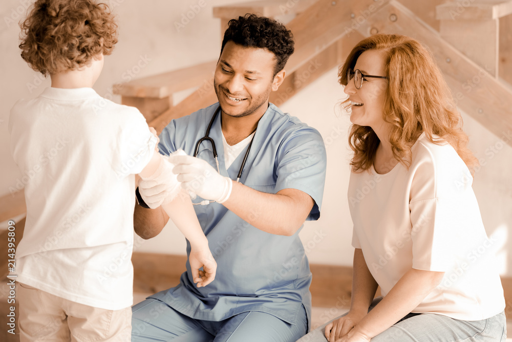 Visiting doctor. Cheerful woman feeling happiness while looking at her son and sitting in semi position Visiting doctor. Cheerful woman feeling happiness while looking at her son and sitting in semi position