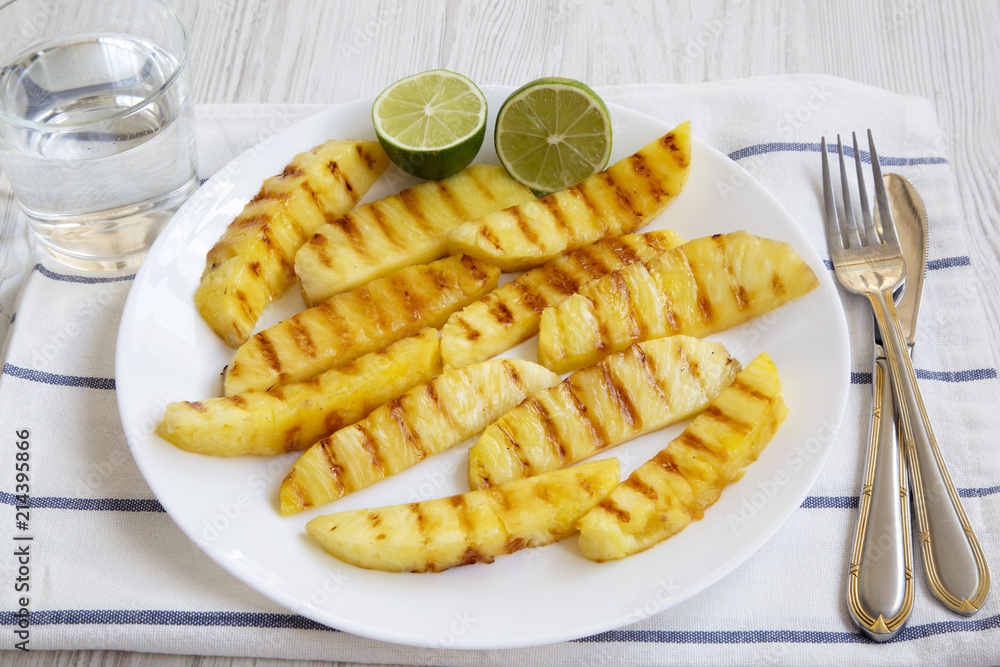 Grilled pineapple wedges with lime and glass of water, side view. Summer food. Grilled pineapple wedges with lime and glass of water, side view. Summer food.