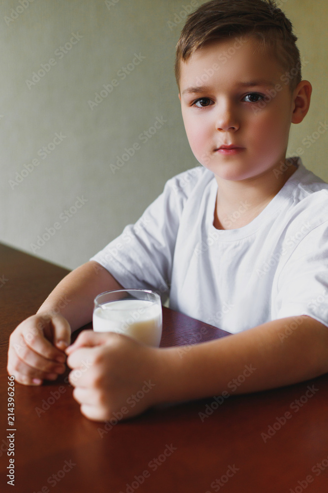 The boy looks sadly into the distance. A glass of milk, a morning kitchen. The boy looks sadly into the distance. A glass of milk, a morning kitchen.