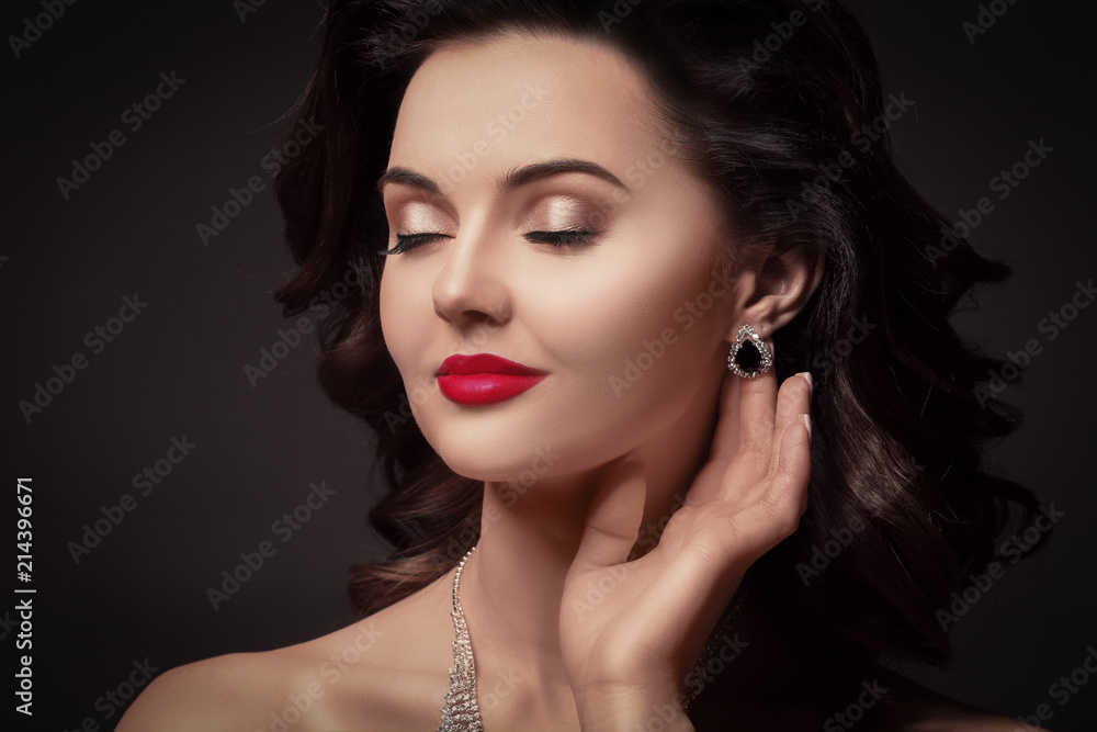 Portrait of beautiful young woman with luxury jewelry on dark background