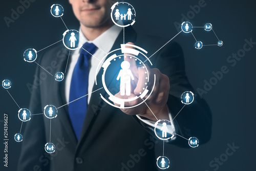 Businessman pushing button on virtual screen against dark background photo