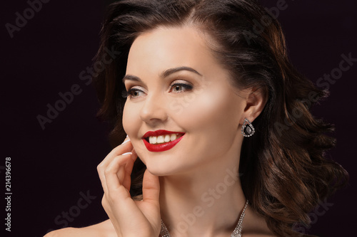 Portrait of beautiful young woman with luxury jewelry on dark background
