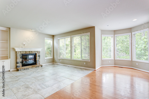 Empty living area with tons of light and fireplace.