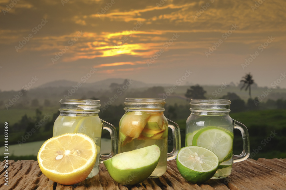 ,Lime green apple and lemon detox water in the morning on green nature and sunrise background ,Lime green apple and lemon detox water in the morning on green nature and sunrise background