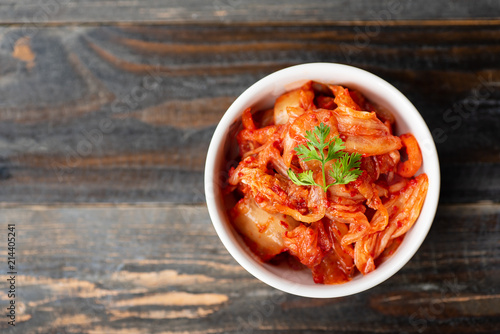 Kimchi cabbage in a bowl on wooden background, top view, Korean food