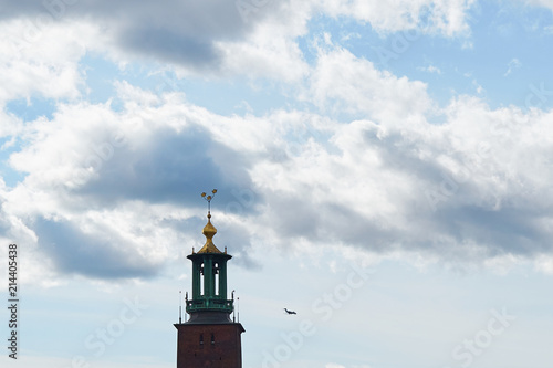Airplane landing behind the Stockholm City Hall in a blue cloudy sky.