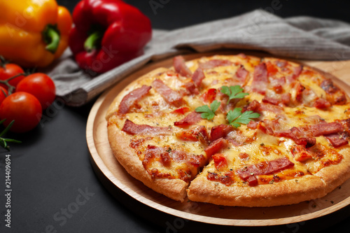 Delicious Italian pizza sliced ham, bacon and cheese with food ingredients on old kitchen table.