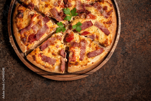 Delicious Italian pizza sliced ham, bacon and cheese with food ingredients on old kitchen table.