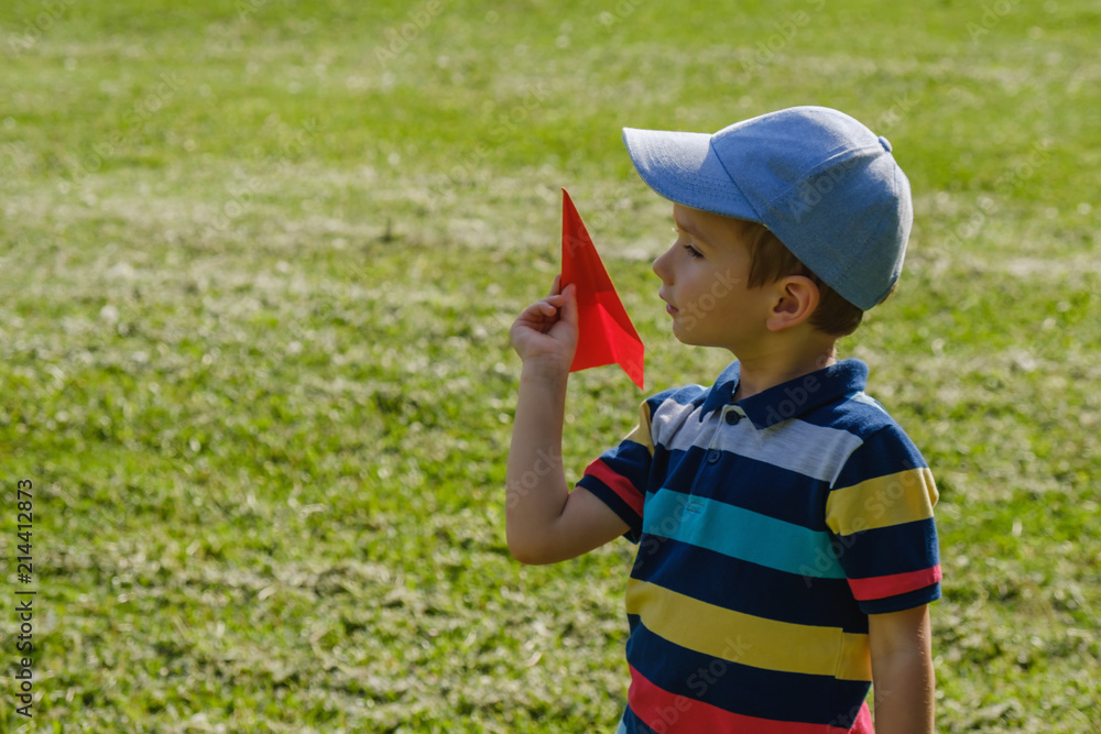 Boy playing with a toy red plane at park on a sunny day