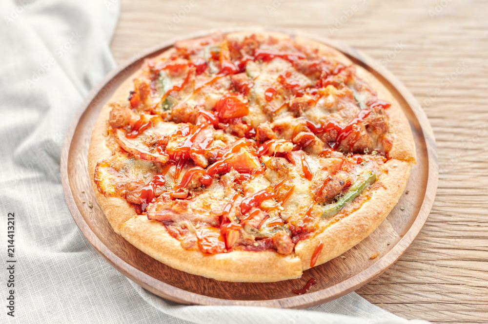 Delicious Italian pizza sliced with bacon, cheese, tomato, capsicum on wooden plate. Delicious Italian pizza sliced with bacon, cheese, tomato, capsicum on wooden plate.