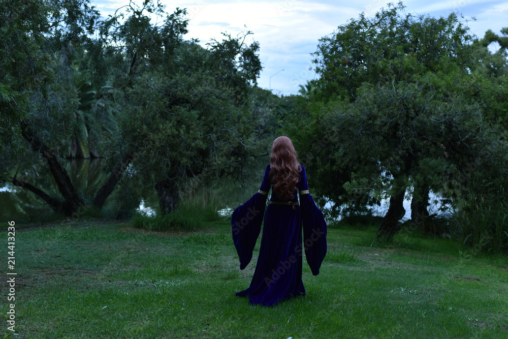 full length portrait of girl wearing long blue medieval gown. wandering through a forest landscape. full length portrait of girl wearing long blue medieval gown. wandering through a forest landscape.