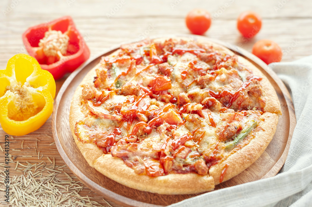Delicious Italian pizza sliced with bacon, cheese, tomato, capsicum on wooden plate.