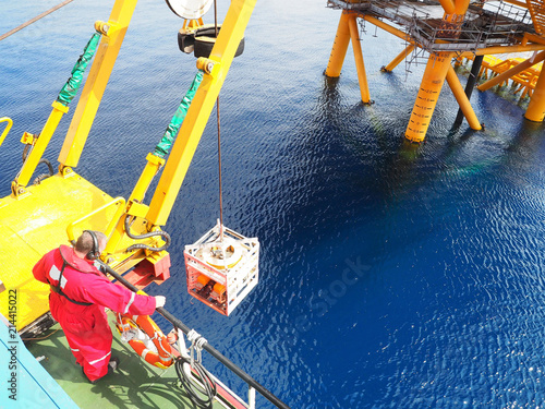 ROV crew launches ROV into the sea for subsea inspection work near static platform.
