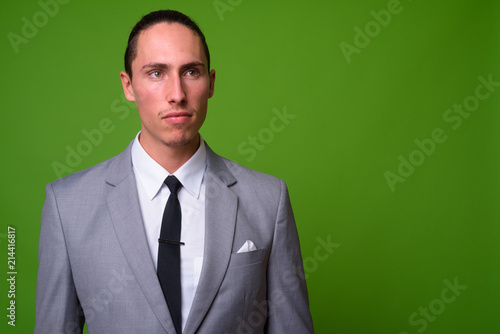 Young handsome businessman against green background