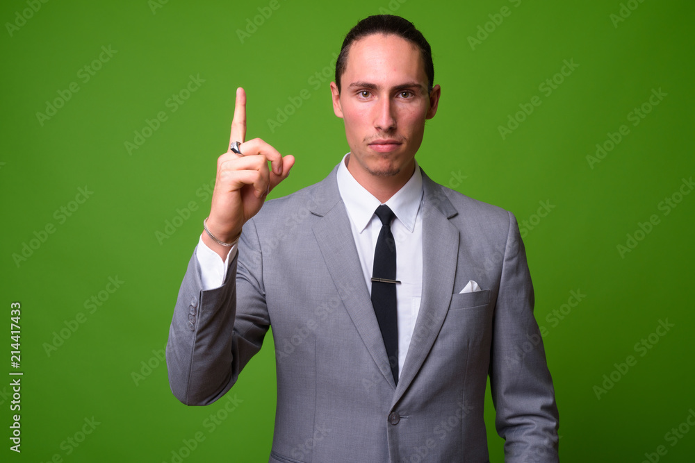 Young handsome businessman against green background Young handsome businessman against green background