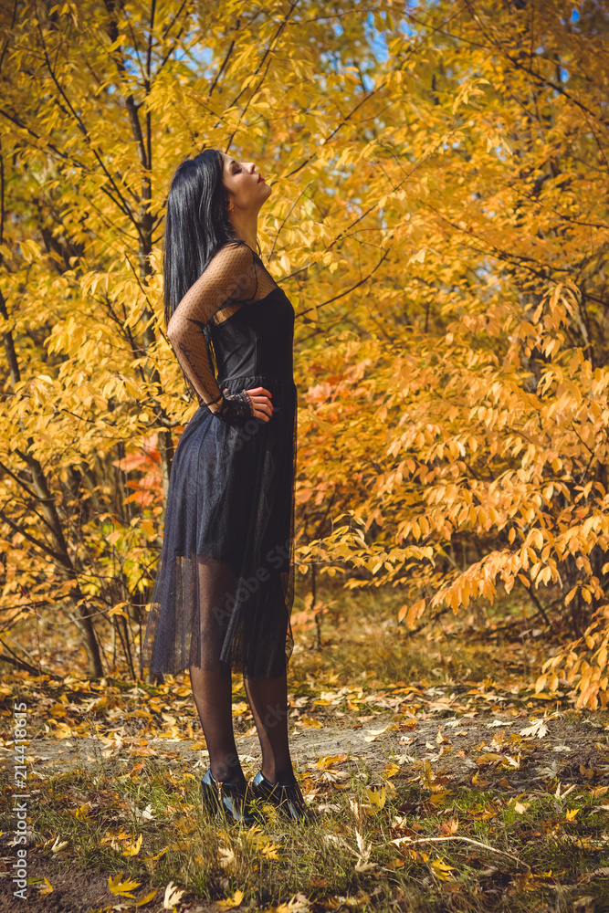 Portrait of chic dark-haired tattooed young woman with perfect make up wearing lace dress standing in the abandoned garden. Gothic lady Portrait of chic dark-haired tattooed young woman with perfect make up wearing lace dress standing in the abandoned garden. Gothic lady