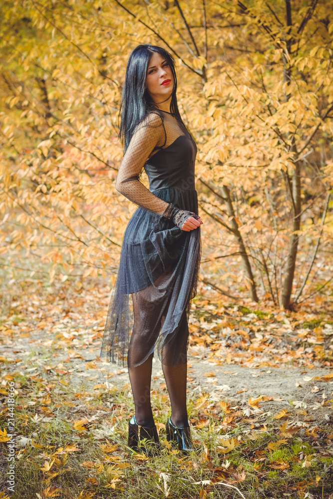 Portrait of chic dark-haired tattooed young woman with perfect make up wearing lace dress standing in the abandoned garden. Gothic lady Portrait of chic dark-haired tattooed young woman with perfect make up wearing lace dress standing in the abandoned garden. Gothic lady