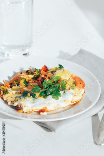 Scrambled eggs with tomatoes and greens on an white background
