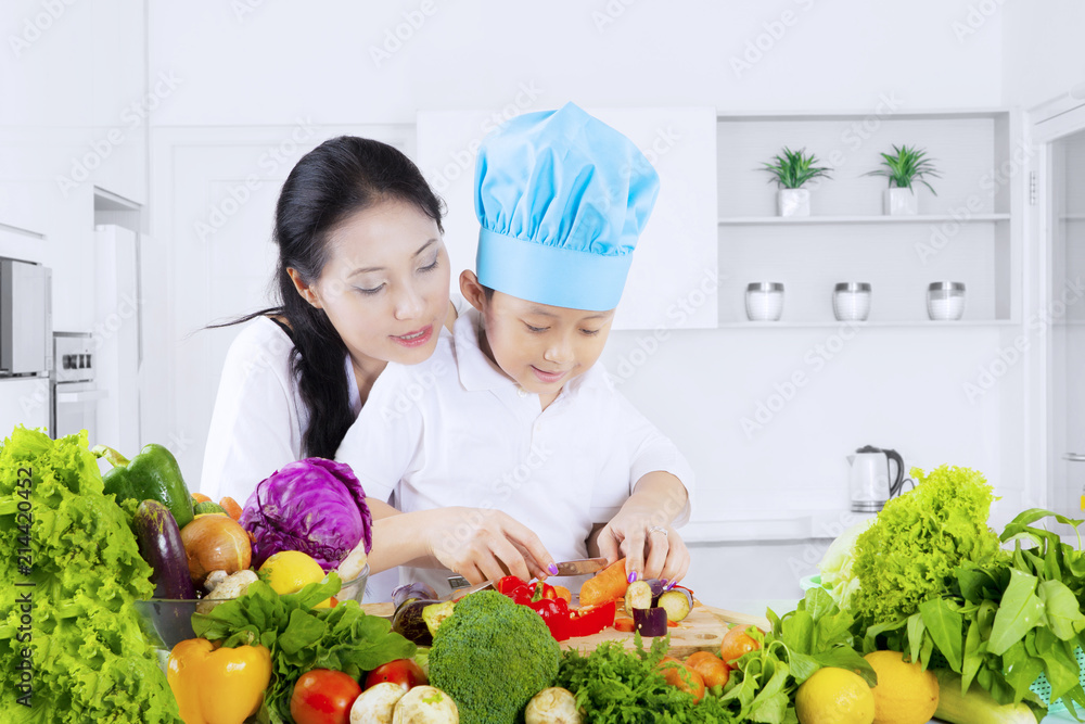 Child cutting vegetables with her mother Child cutting vegetables with her mother