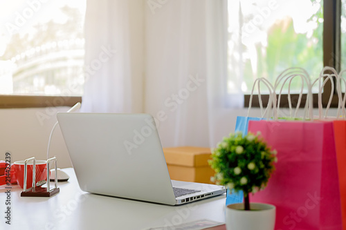 Laptop and small shopping bag on table. Internet shopping concept