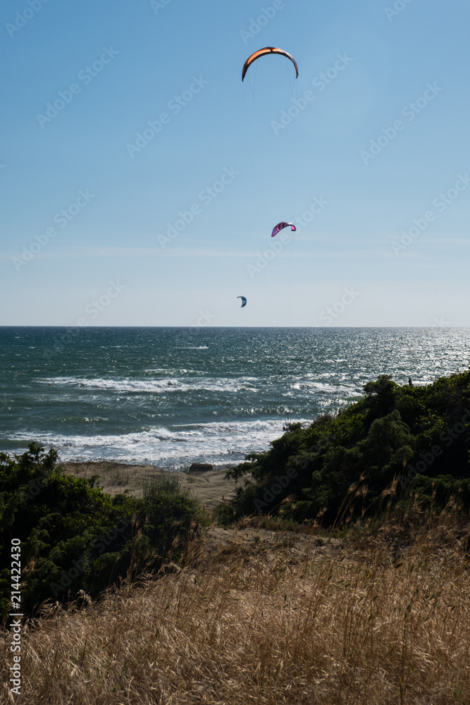 Vertical view from the sand dunes of kitesurfing under a bright sun on a blue sky. Vertical view from the sand dunes of kitesurfing under a bright sun on a blue sky.
