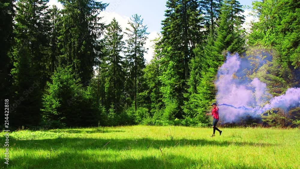 SLOWMO, young woman frolicks around a grassy clearing with a blue smoke bomb in Black Forest, Germany SLOWMO, young woman frolicks around a grassy clearing with a blue smoke bomb in Black Forest, Germany