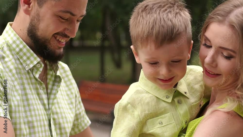 Close-up of a happy smiling little boy in the hands of a loving mom and dad in the park. Close-up of a happy smiling little boy in the hands of a loving mom and dad in the park.