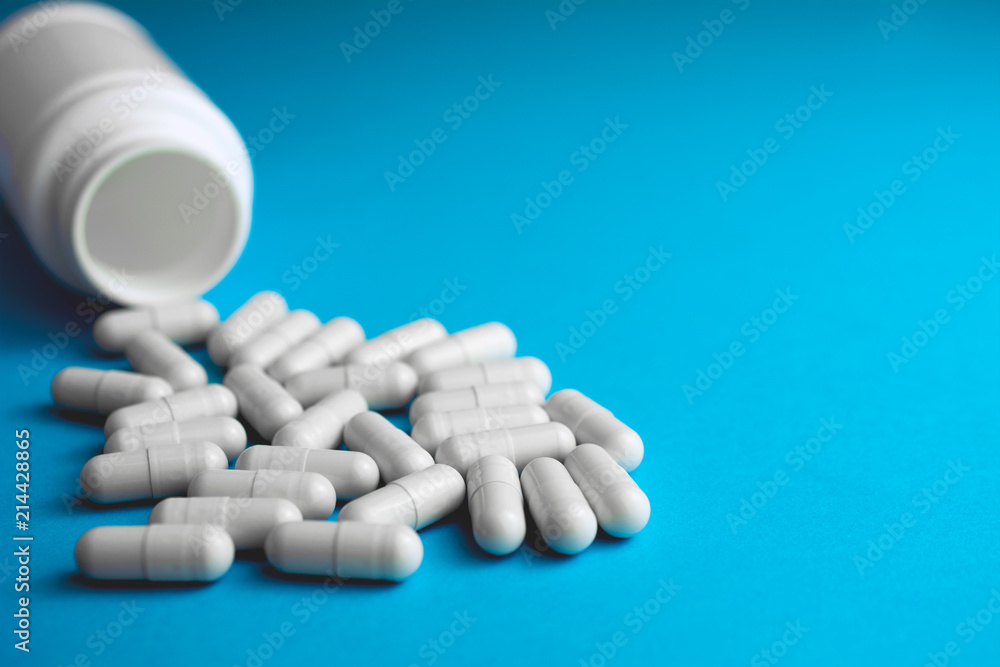 Pills tablets capsule plastic drugs bottle blue background. Medicine Pharmaceutical medicament concept.