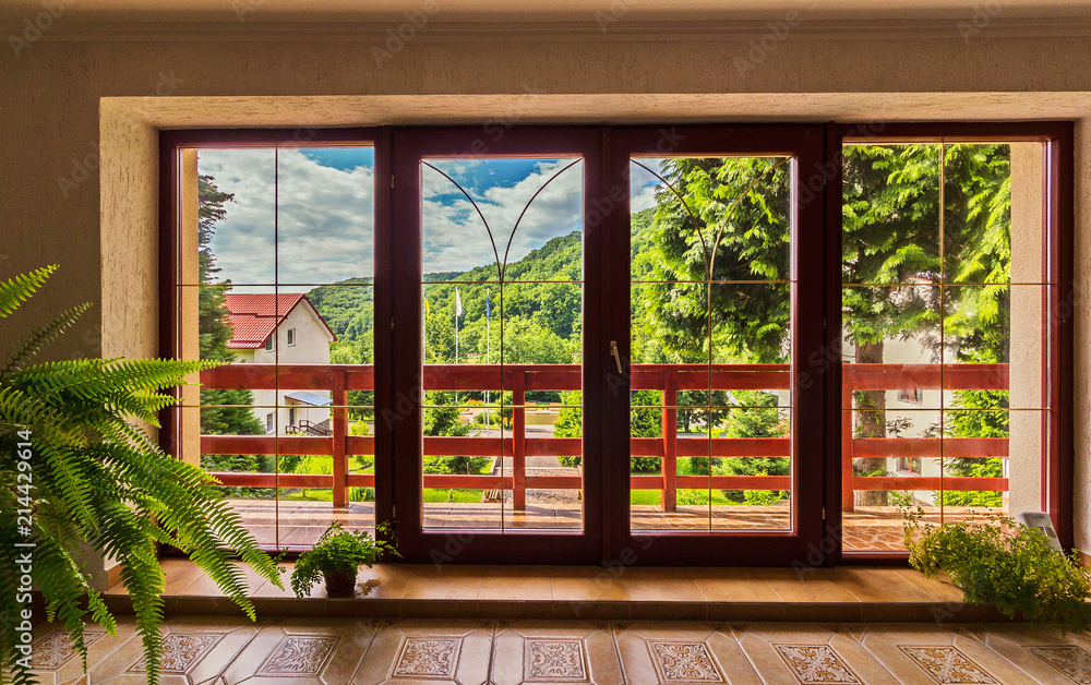 large glass doors in the house over which a panorama of mountains under the blue sky opens