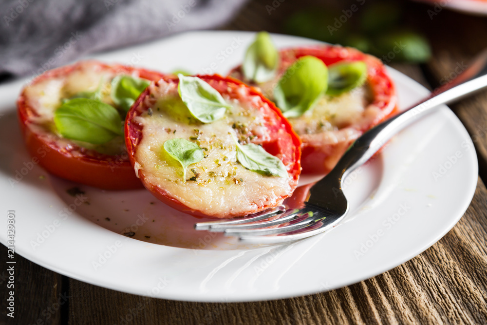Tomatoes baked under Parmesan with fresh basil