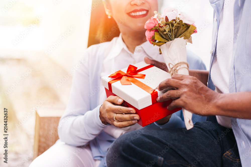 Couple of middle aged woman and senior man giving a surprise gift on her special day such as birthday or wedding anniversary. Celebration and holiday concept