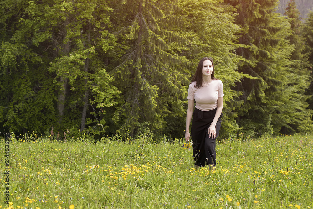 Young woman with a bouquet of flowers walking in a meadow. Young woman with a bouquet of flowers walking in a meadow.