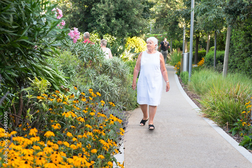 Mature woman going for a walk through an urban park for exercise