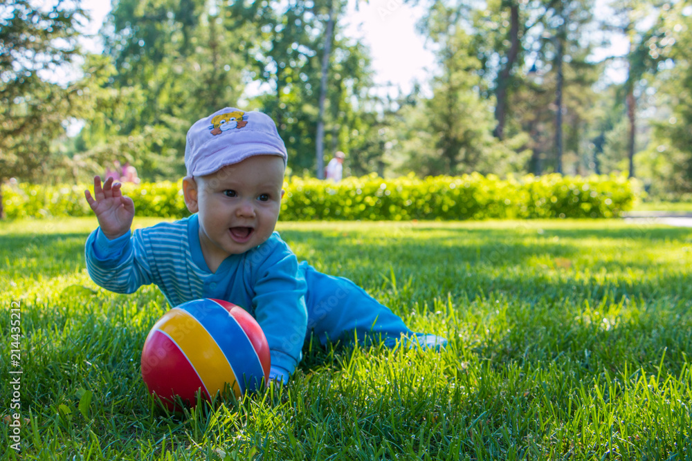 baby sitting on the soft grass in the city Park with his colorful ball baby sitting on the soft grass in the city Park with his colorful ball