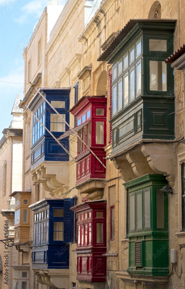 Red blue and green maltese balconies and ochre walls in Valletta narrow streets, the capital city of Malta island