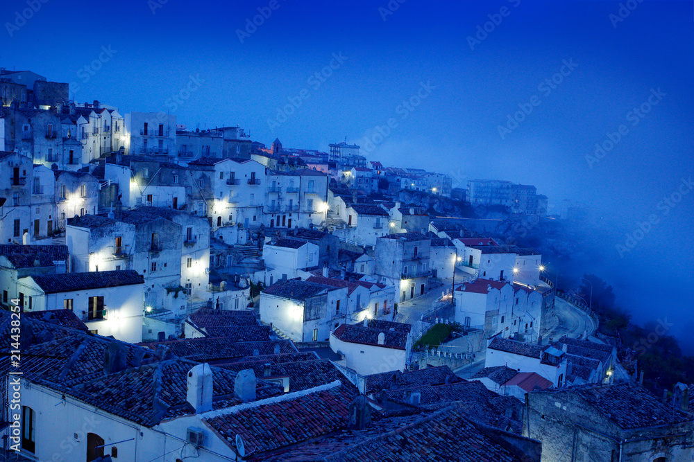Monte Sant'Angelo town in Foggia, Gargano peninsula in Italy. Night scene with old buildings with lights.  Travel in Europe, magic evening.
