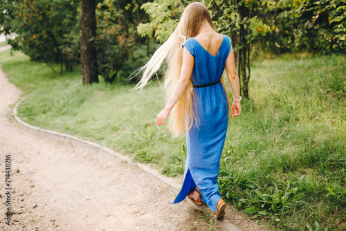 Young beautiful girl with long hair in a blue dress outdoors, woman in nature, professional make-up and hairstyle