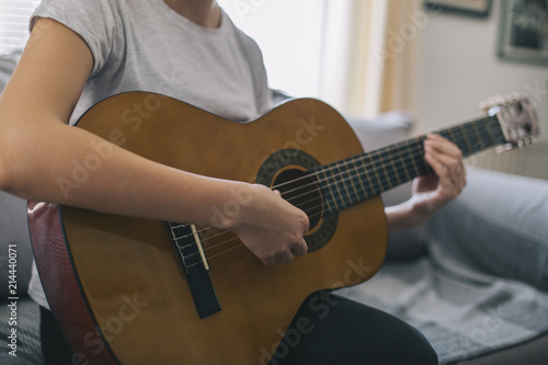 A young girl learns to play guitar. Woman's hands playing acoustic guitar.